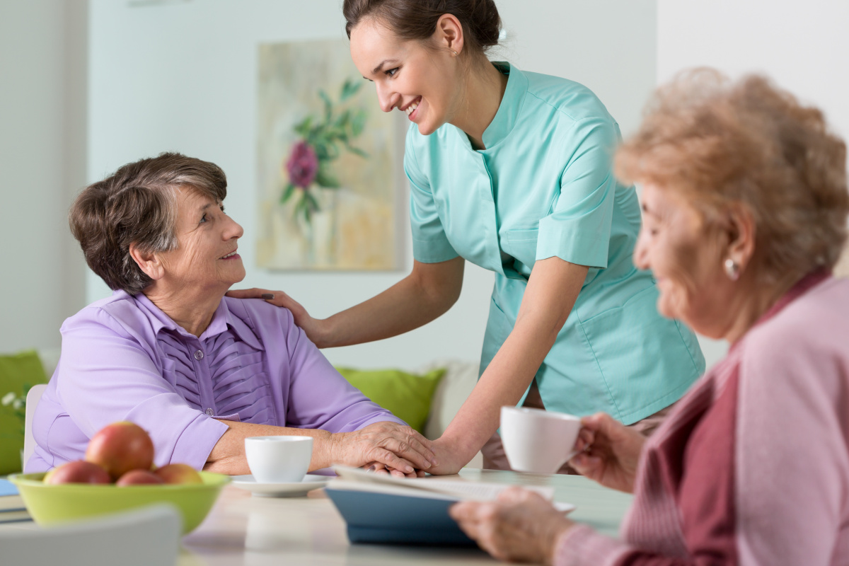Two older women having a nice conversation with young nurse.
