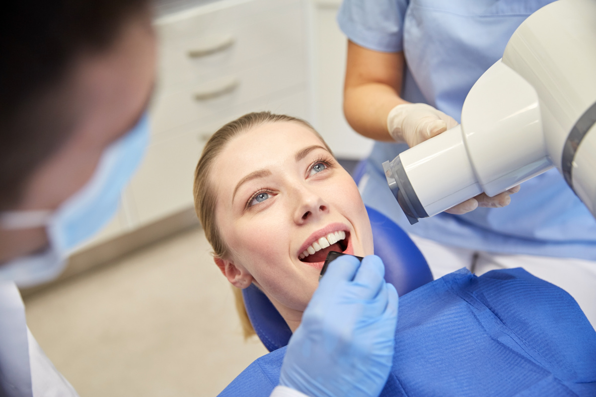 Young Woman in Dental Exam Chair Getting an X-Ray with Dentist Out of Focus