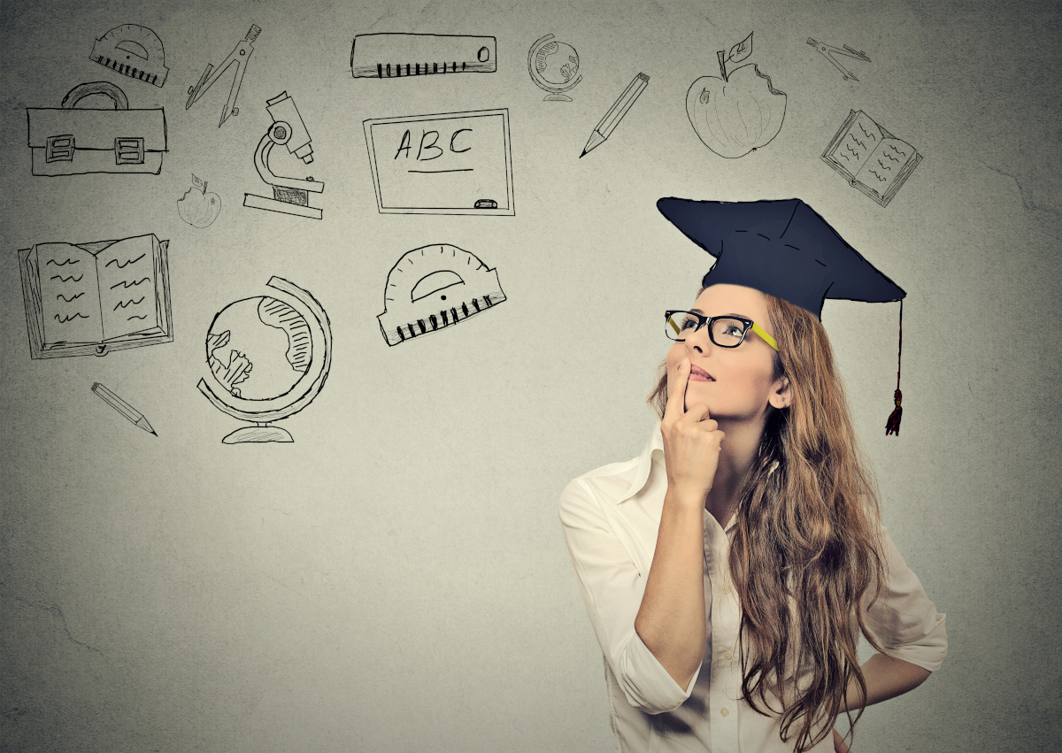 Young Woman In Glasses and Graduation Cap Looking at Chalkboard with Information