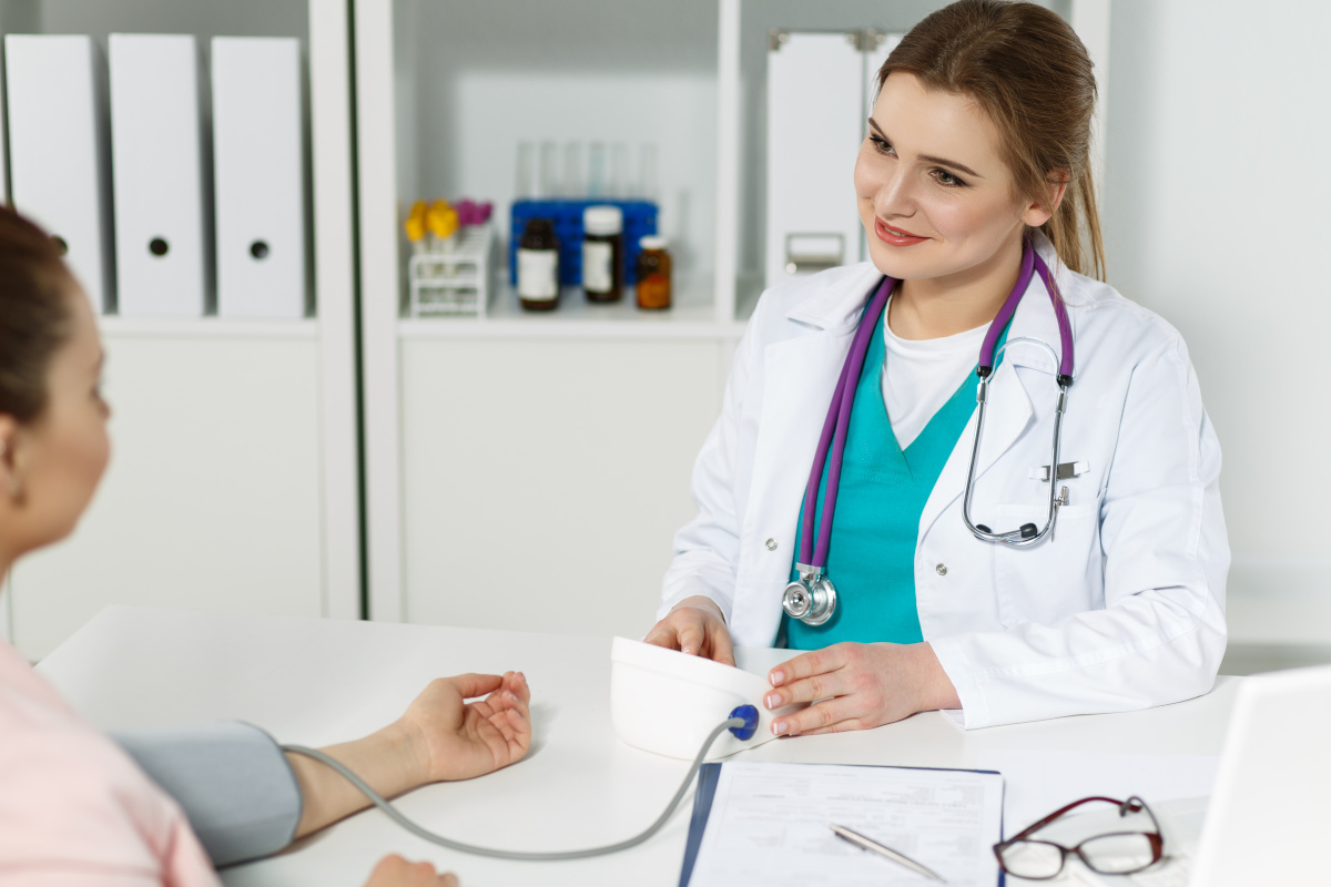 Smiling female doctor taking patient's blood pressure.