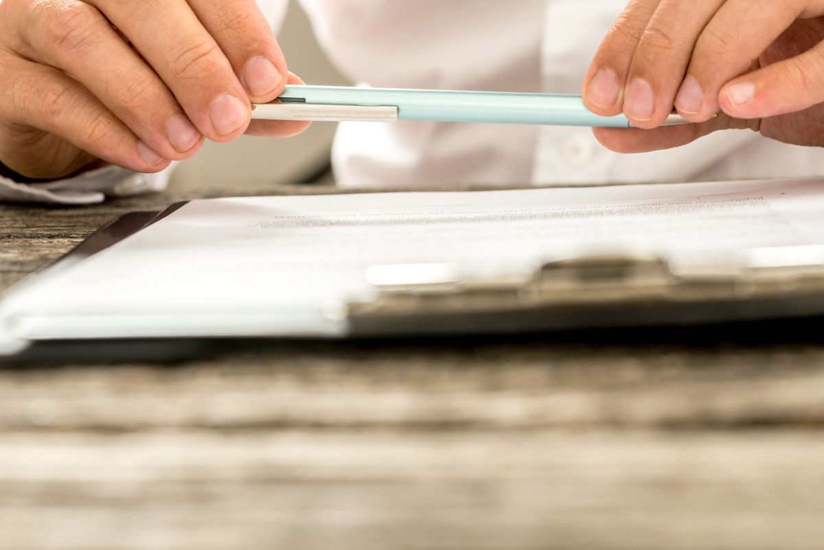 Man Holding Pen Above Legal Document