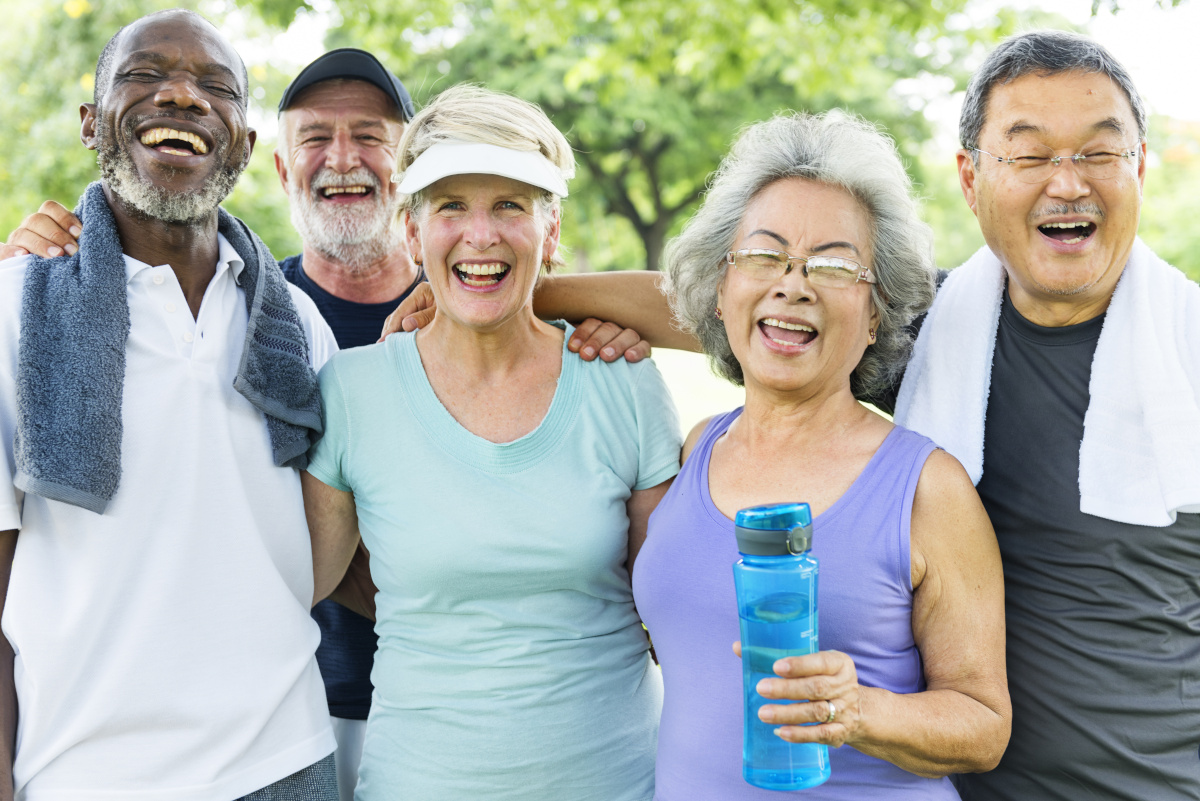 A group of older people standing with each other after excersicing, arms around each other's shoulders and smiling