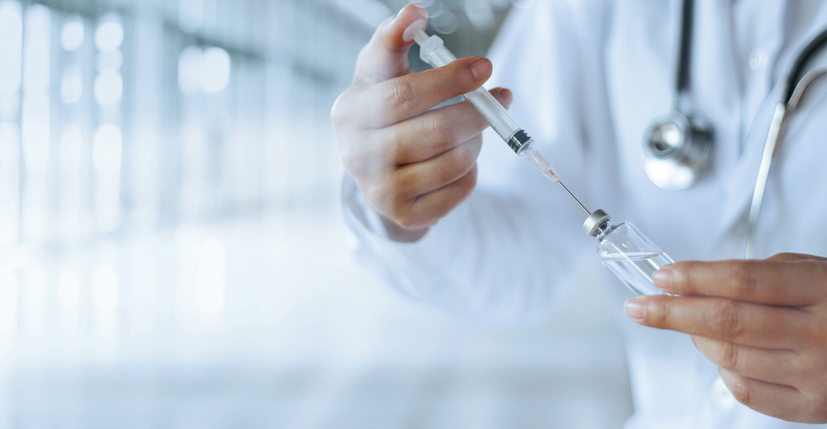 Doctor using a syringe to get a vaccine out of a bottle 